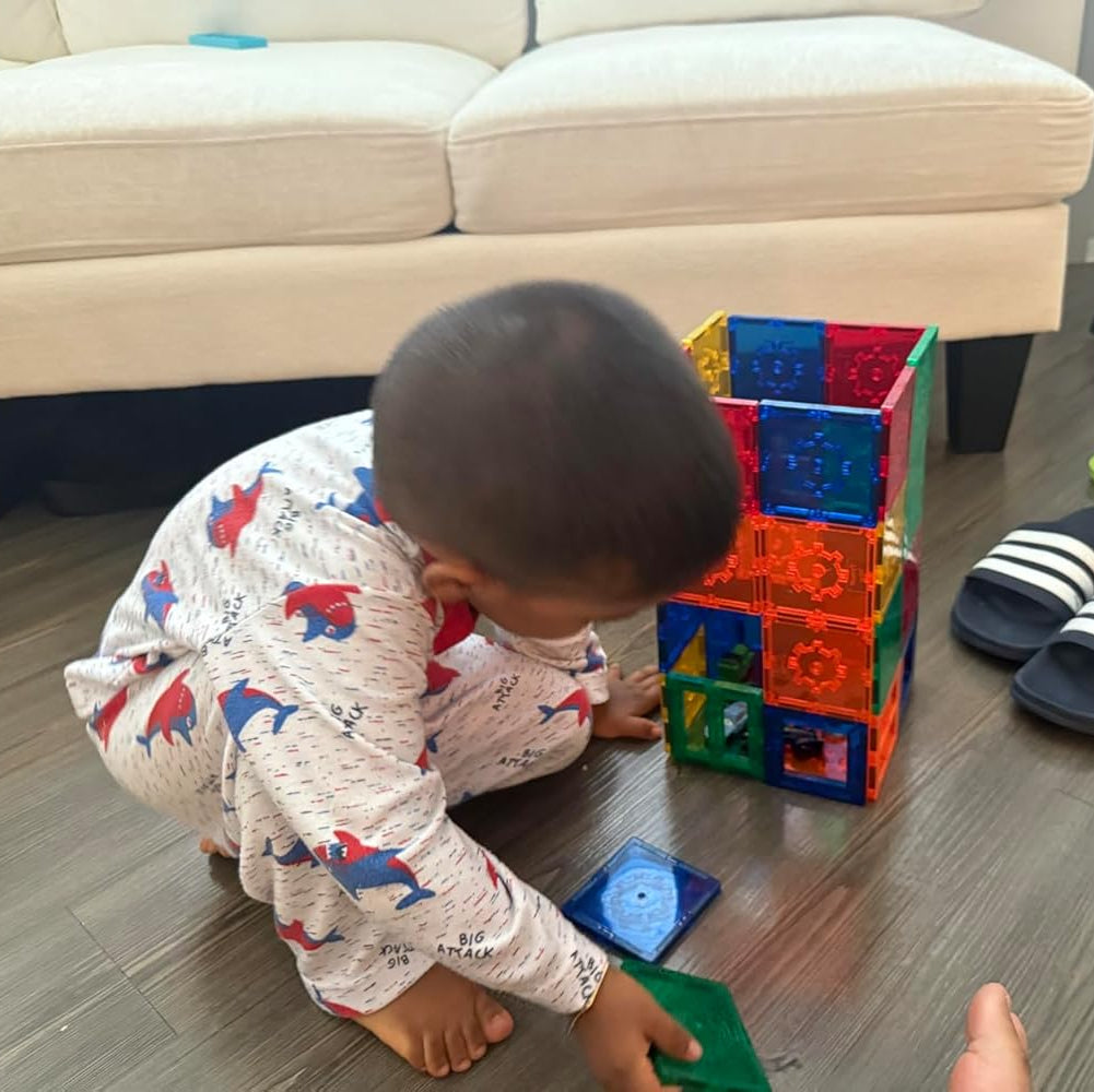 Child playing with colorful building blocks on a wooden floor.