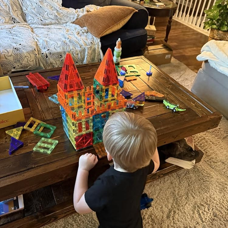 Child playing with colorful building blocks on a wooden coffee table in a living room.